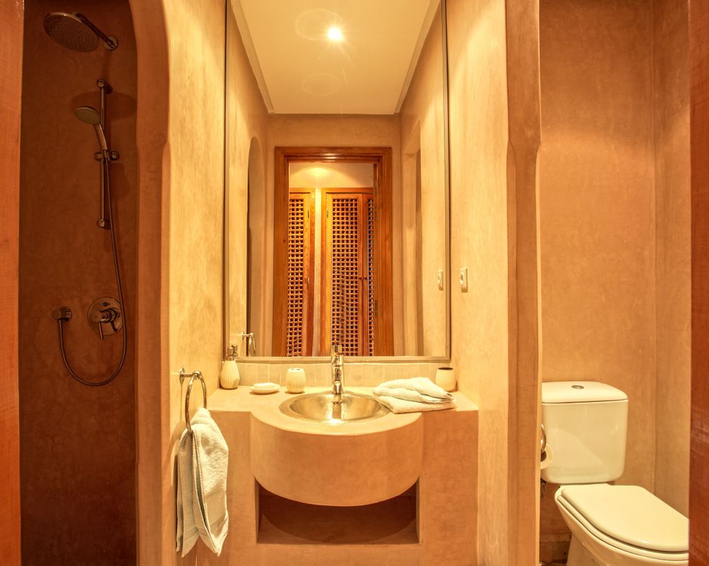 Un baño con ducha, lavabo, espejo e inodoro.