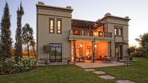 A two-story house with a covered patio, outdoor seating area, and a well-maintained garden. - Villa avec piscine privée et Golf (Marrakech)