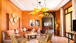 A cozy living room with a sofa, chairs, a coffee table, and a TV. - Villa avec piscine privée et Golf (Marrakech)