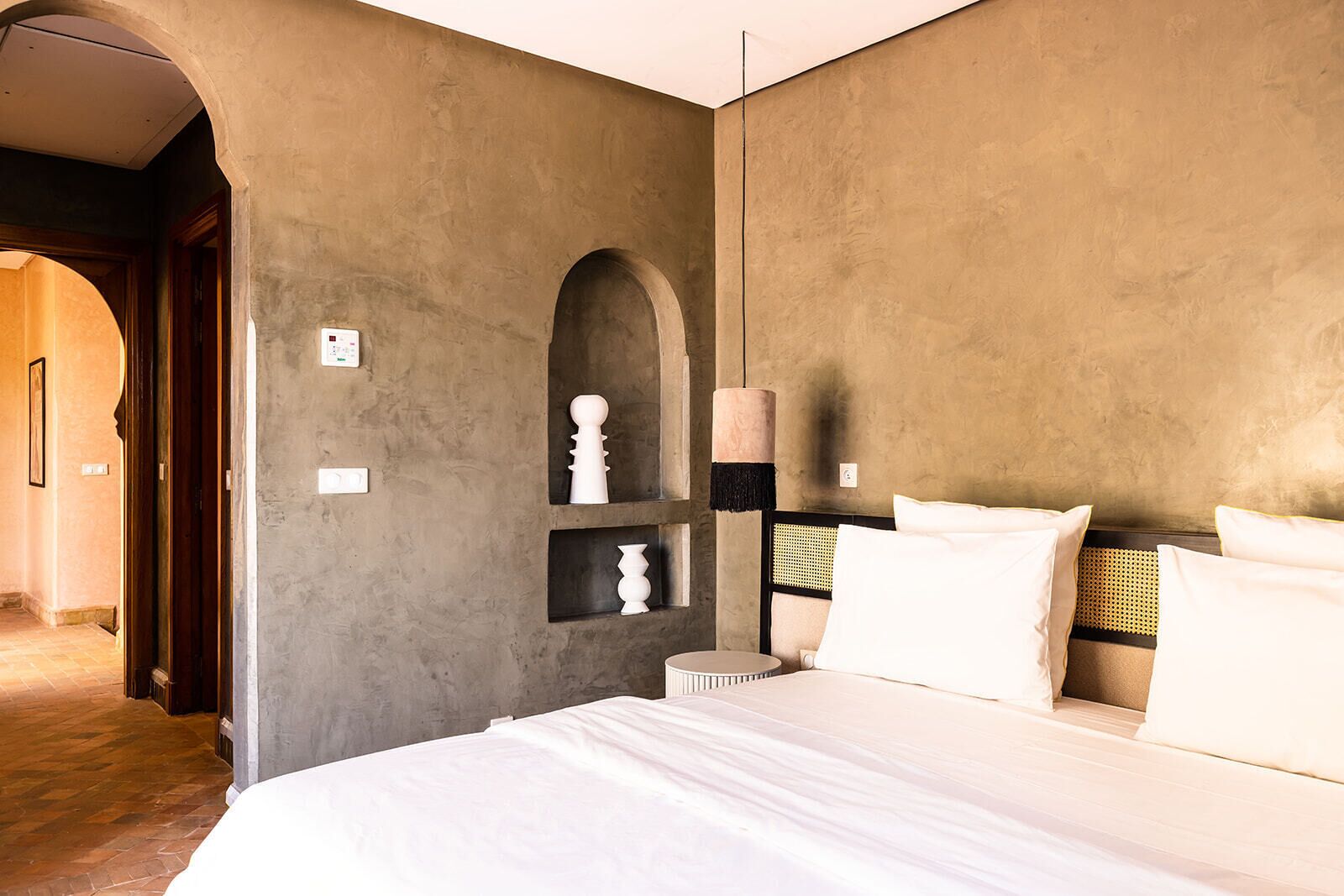 Ein Schlafzimmer mit einem großen Bett, einem Kopfteil mit gewebtem Rücken und einem Wandregal mit Dekoration.