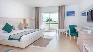A hotel room with a bed, a desk, a chair, a TV, and a balcony with a view of the ocean. - Hotel Nour Congress & Resort (Bizerte)