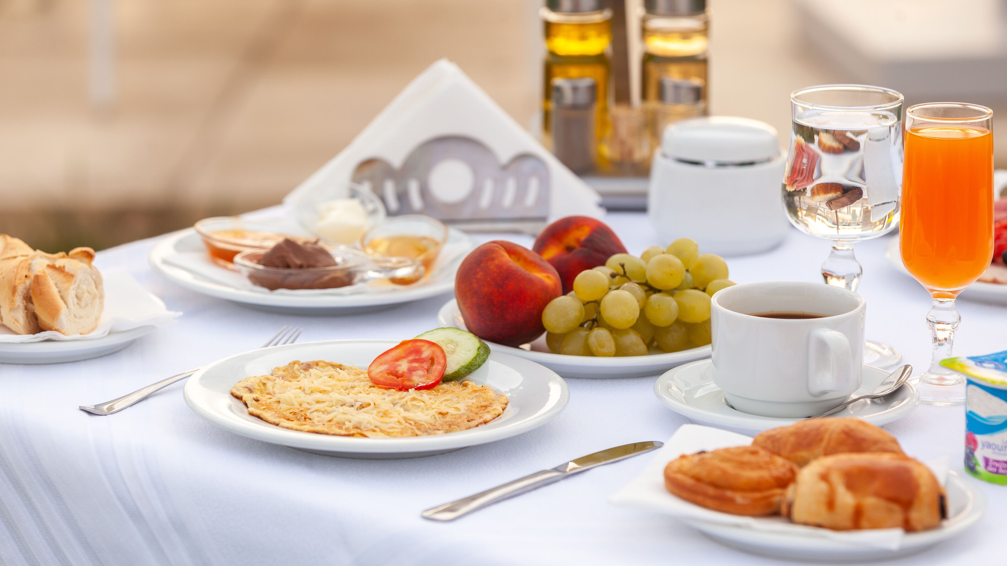 Desayuno servido con platos de comida, una taza de café y un vaso de jugo de naranja.