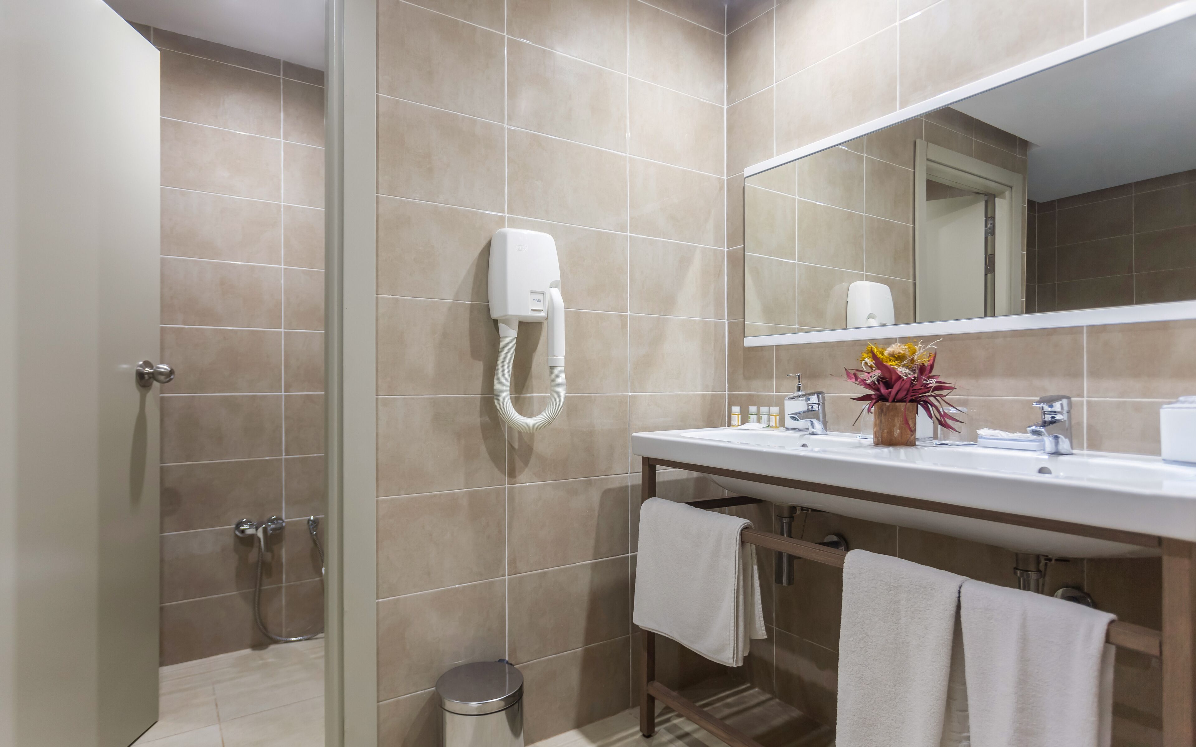 A modern bathroom with a shower, a sink with a mirror, and a towel rack.