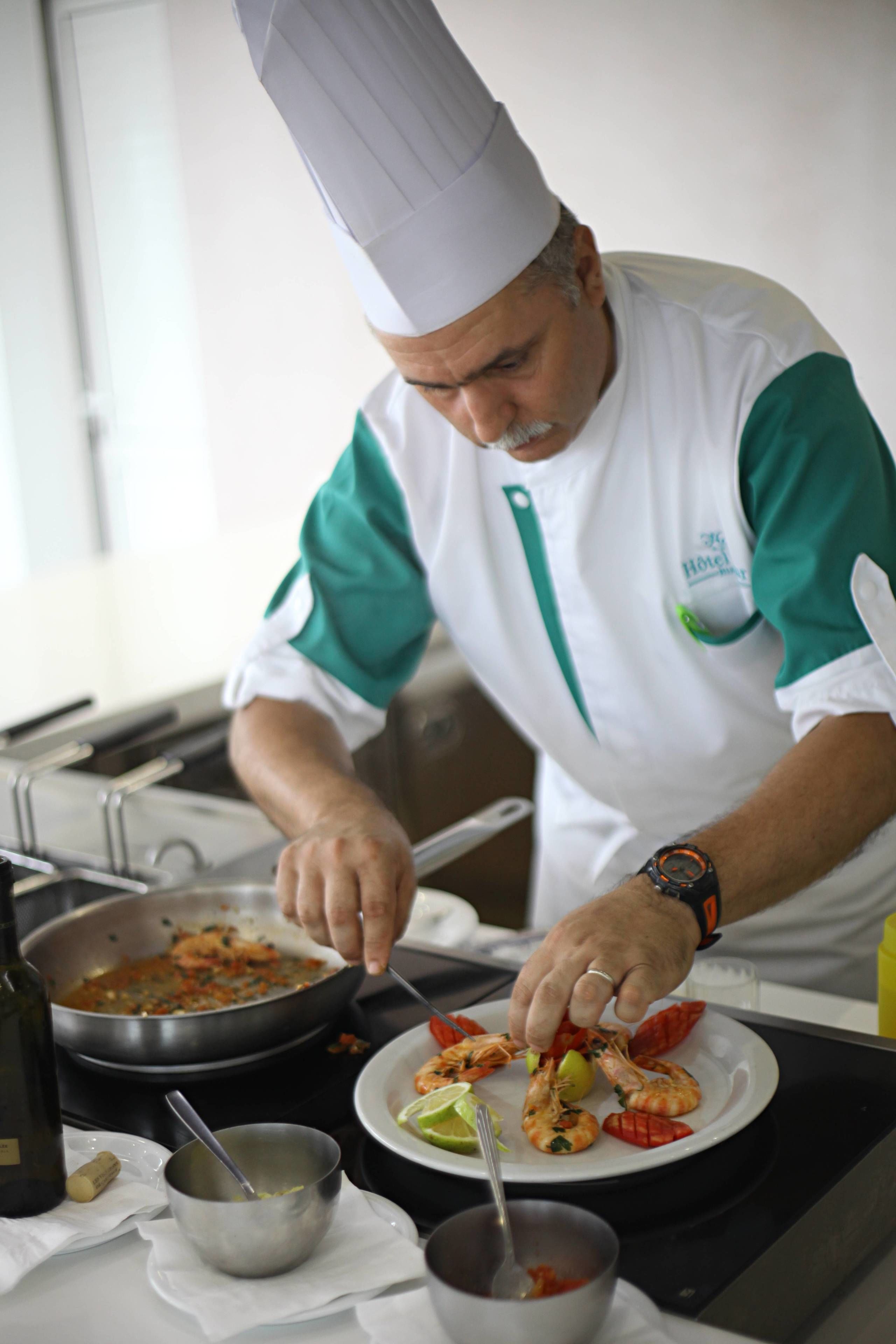 A chef preparing a dish with shrimp and lime in a kitchen.