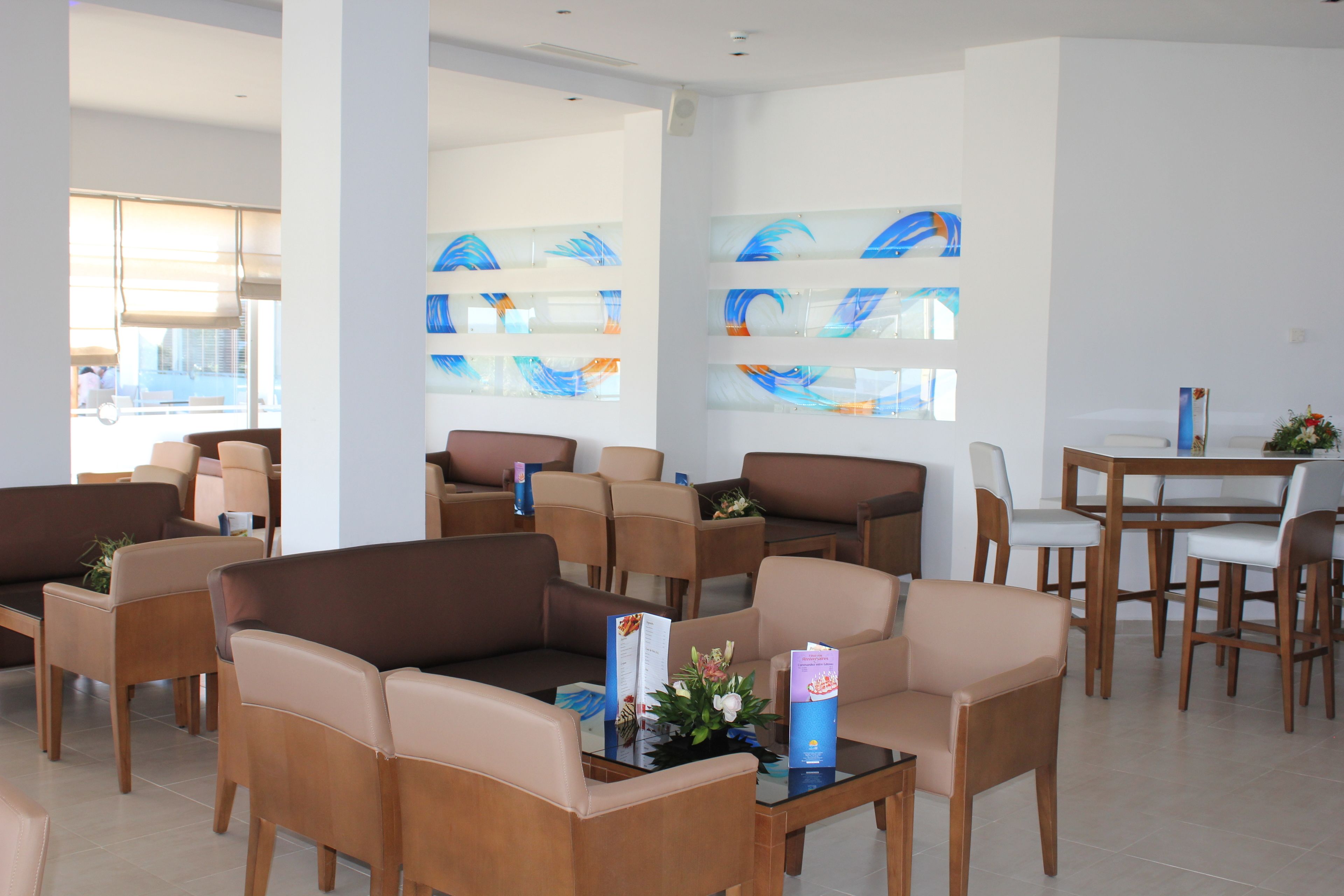 A modern hotel lobby with seating areas, a reception desk, and abstract art on the walls.