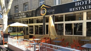 A hotel with outdoor seating, a sign reading "REHôtel", and a visible entrance. - Rev Hotel (Lamalou-les-Bains)