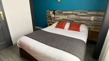 Une chambre d’hôtel avec un lit, un mur d’accent bleu, une tête de lit en bois et un tableau encadré accroché au mur.