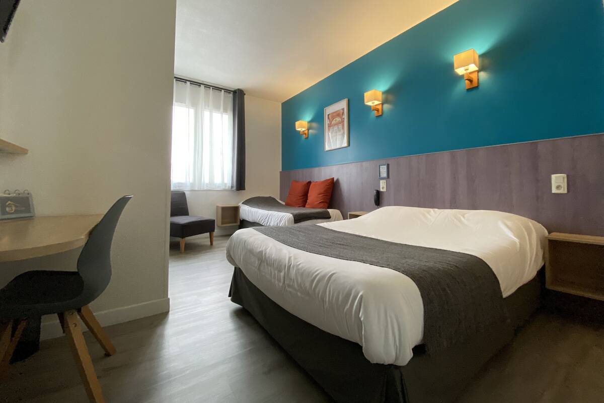 A modern hotel room with a large bed, a desk, and a chair.
