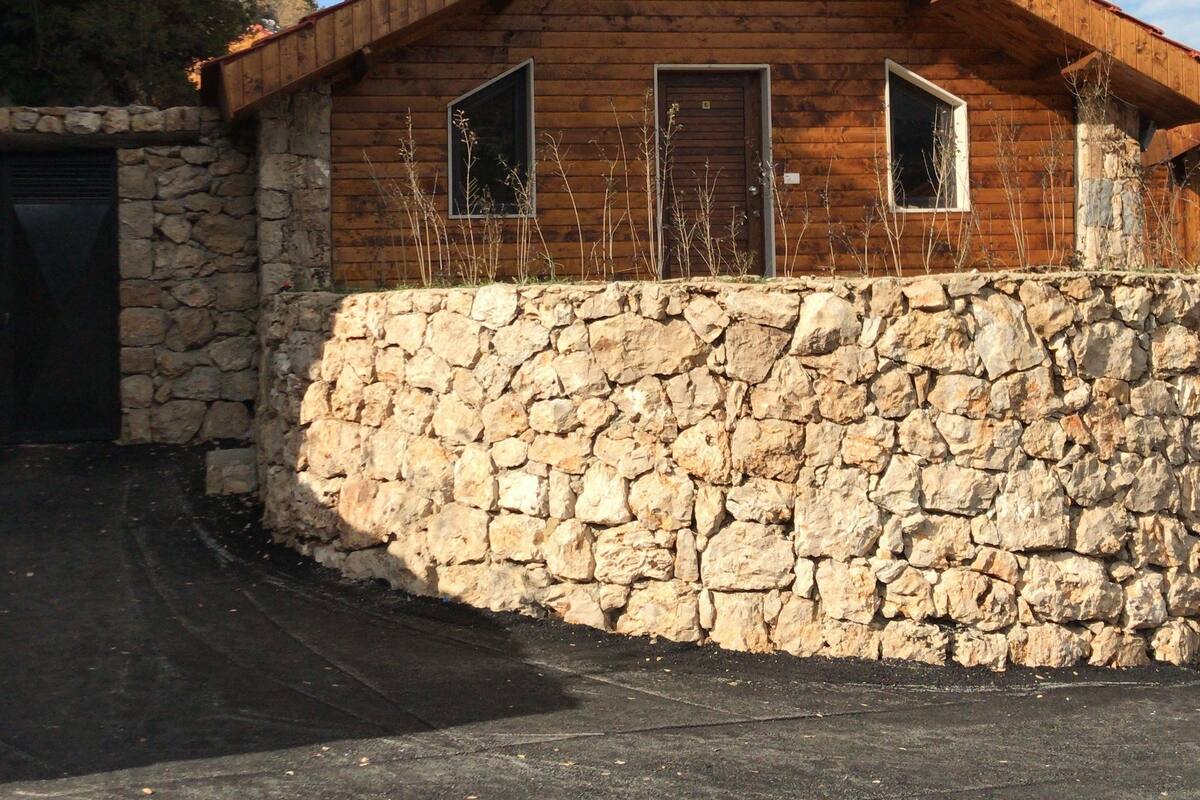 Eine rustikale Holzhütte mit Stein Fundament und Holzwänden, mit zwei Fenstern und einem Schornstein.
