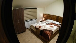 A bedroom with a bed, a wooden wardrobe, a radiator, and a nightstand with a lamp. - Villars (Mayrouba)