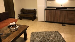 A compact living space with a kitchenette, a wooden bench, a sofa, and a coffee table. - Villars (Mayrouba)