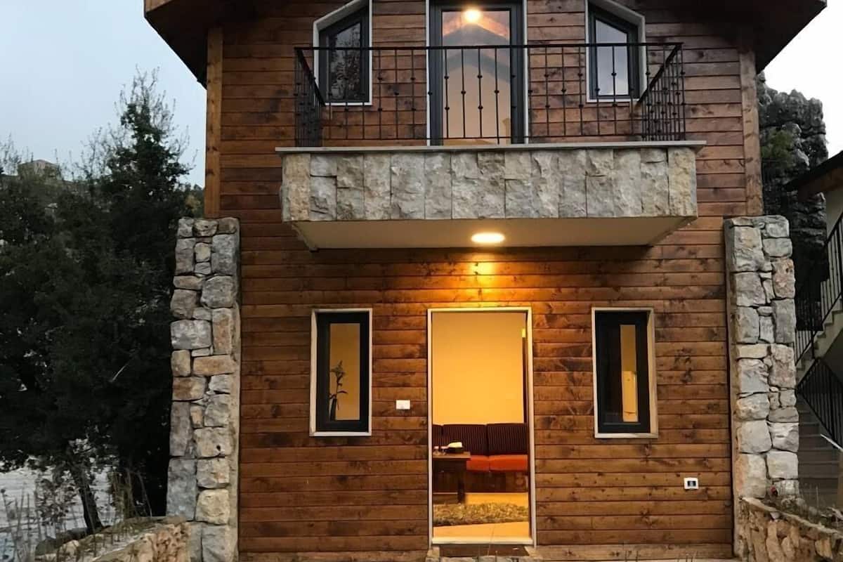 Ein Holzhaus mit Stein Fundament, einem Balkon und einer Tür, die zu einem Innenraum führt.