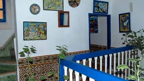 A staircase with a blue railing, surrounded by walls decorated with various framed artworks. - Riad Dar Latifa (Essaouira)