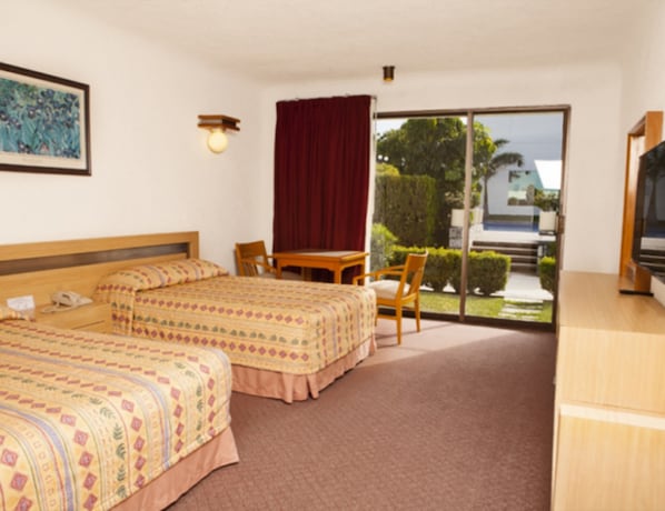A hotel room with two beds, a desk, a chair, and a TV.