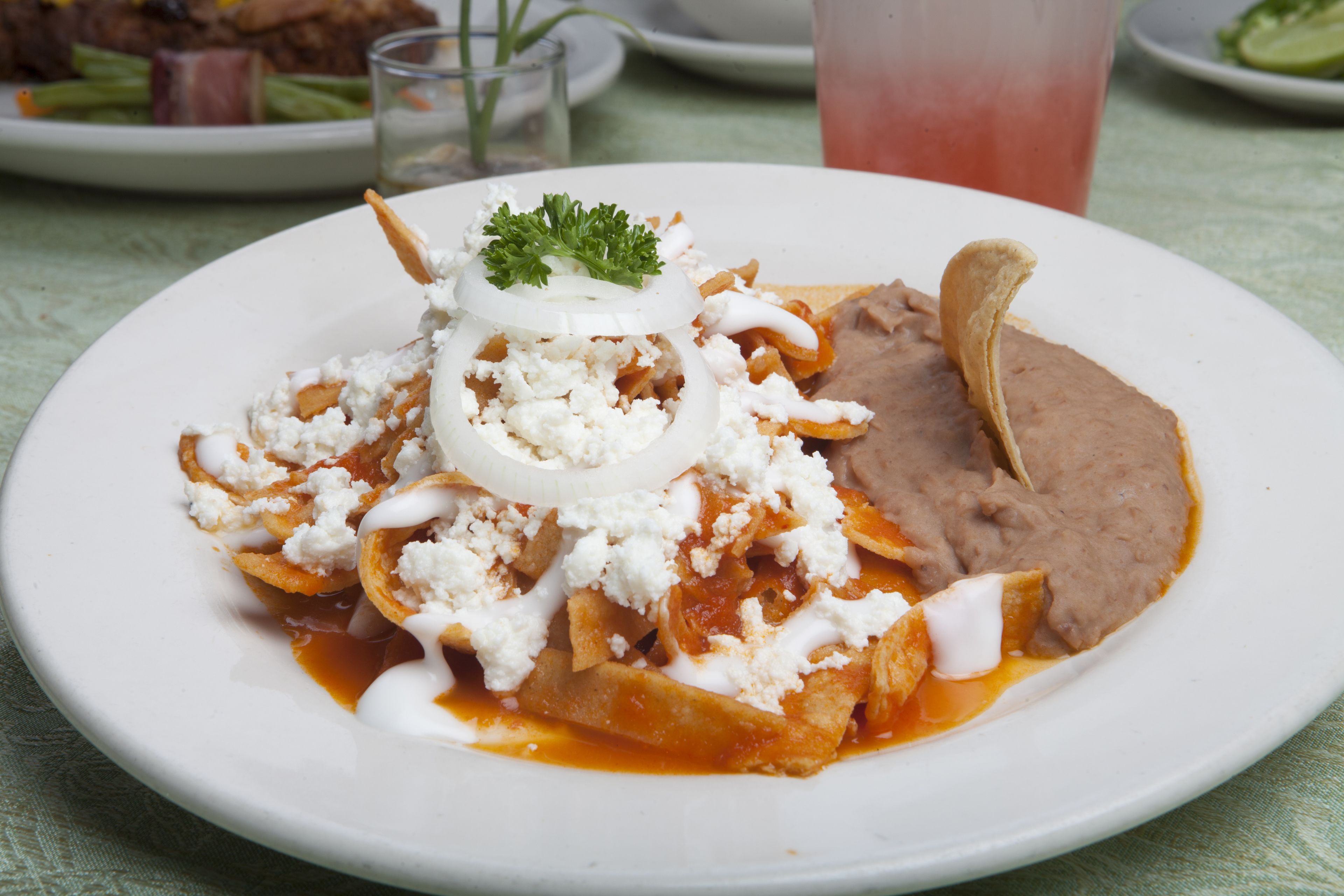 Une assiette de nachos garnis de fromage, de haricots et d’une cuillère de crème aigre.