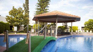 A swimming pool with a green artificial turf area, a covered pavilion, and a rope barrier. - Hotel Paradise Inn (Ciudad Victoria)