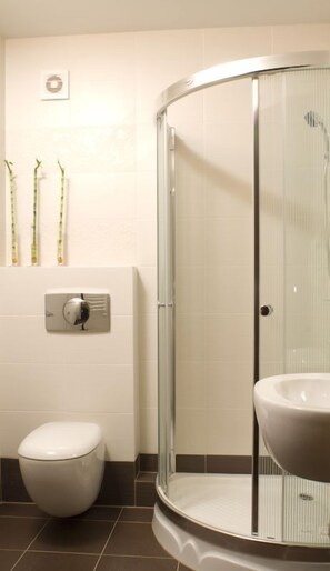 A modern bathroom with a glass shower enclosure, a toilet, and a sink. - Hotel Vesta (Jelesnia)