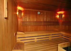 A sauna with wooden benches and slatted backrests, a clock on the wall, and a wooden door. - Hotel Vesta (Jelesnia)
