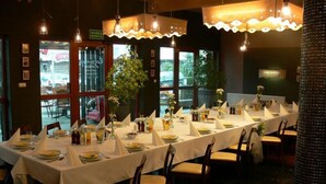 Ein Restaurant mit langen Tischen, gedeckt zum Essen, mit modernem Interieur, Pendelleuchten und großen Fenstern.