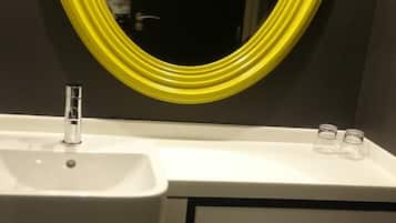 Un baño con un lavamanos blanco, un espejo con marco amarillo y un inodoro.