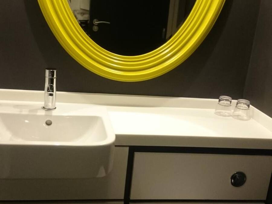 Un baño con un lavamanos blanco, un espejo con marco amarillo y un inodoro.