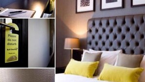 Ein Hotelzimmer mit Bett, Nachttisch, Lampe und einer Wand mit gerahmten Bildern.