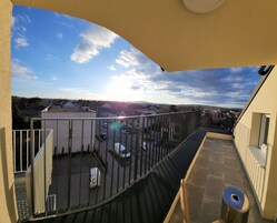 A balcony with a view of a parking lot and buildings in the distance.