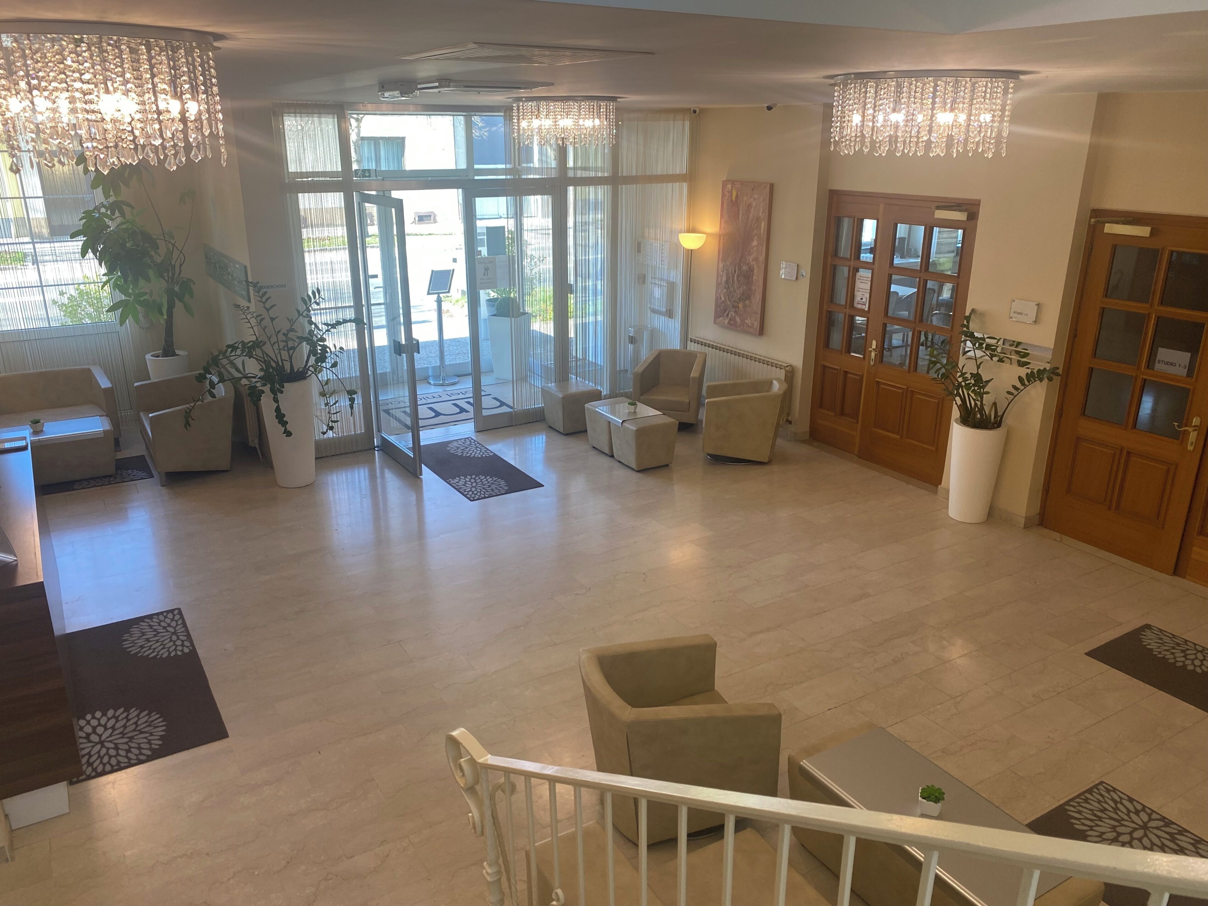 A lobby with a reception desk, seating area, and a staircase.