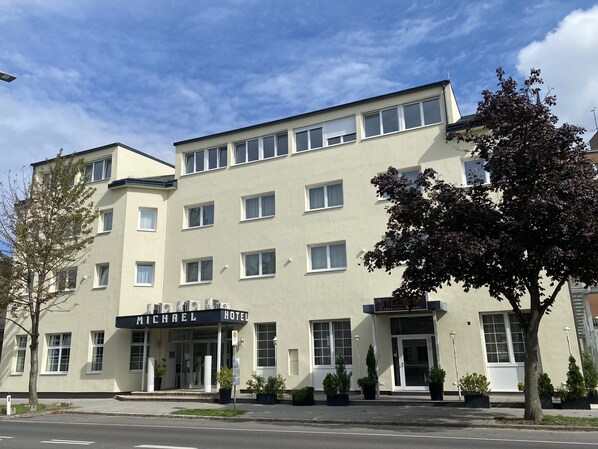 Un hotel con fachada plana, múltiples ventanas y un letrero que dice "MICHAEL HOTEL".