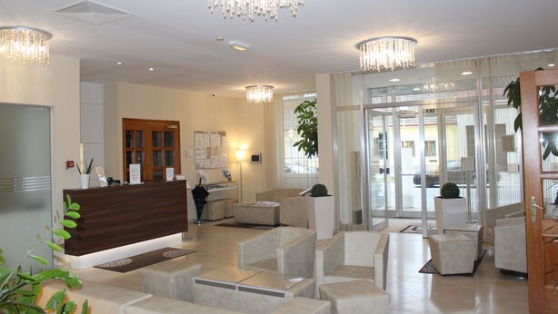 A modern hotel lobby with a reception desk, seating area, and large windows. - Hotel Michael (Gerasdorf bei Wien)
