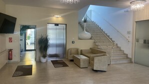 A spacious lobby with a staircase, a reception desk, and a large potted plant. - Hotel Michael (Gerasdorf bei Wien)