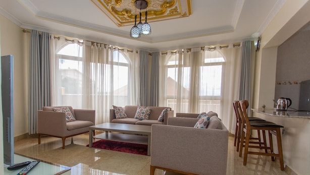 A spacious living room with a sofa set, a coffee table, and a dining area with chairs and a table. - PCG Gishushu Apartment (Kigali)