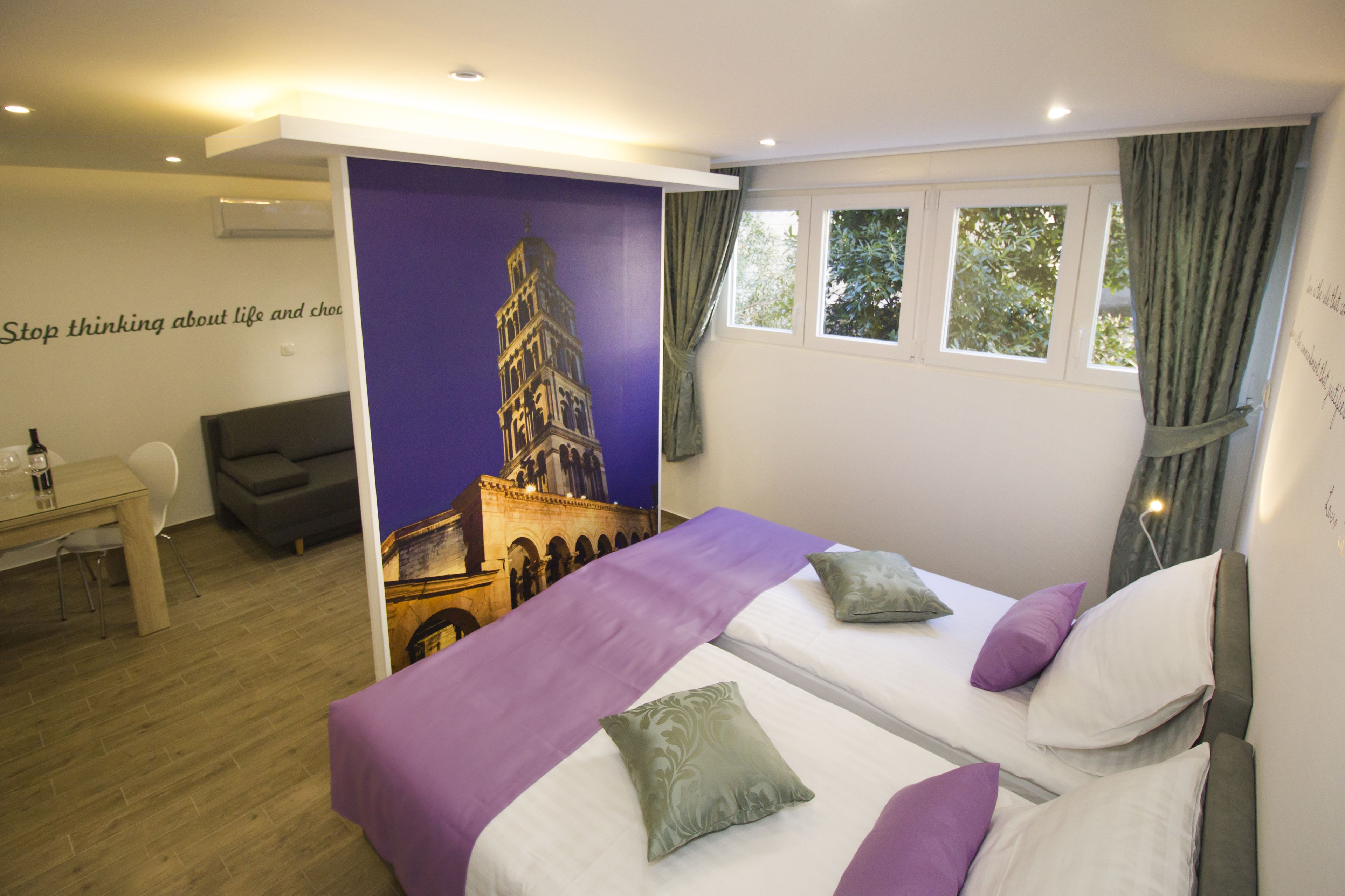 A hotel room with two beds, a desk, a chair, and a large poster of a tower.