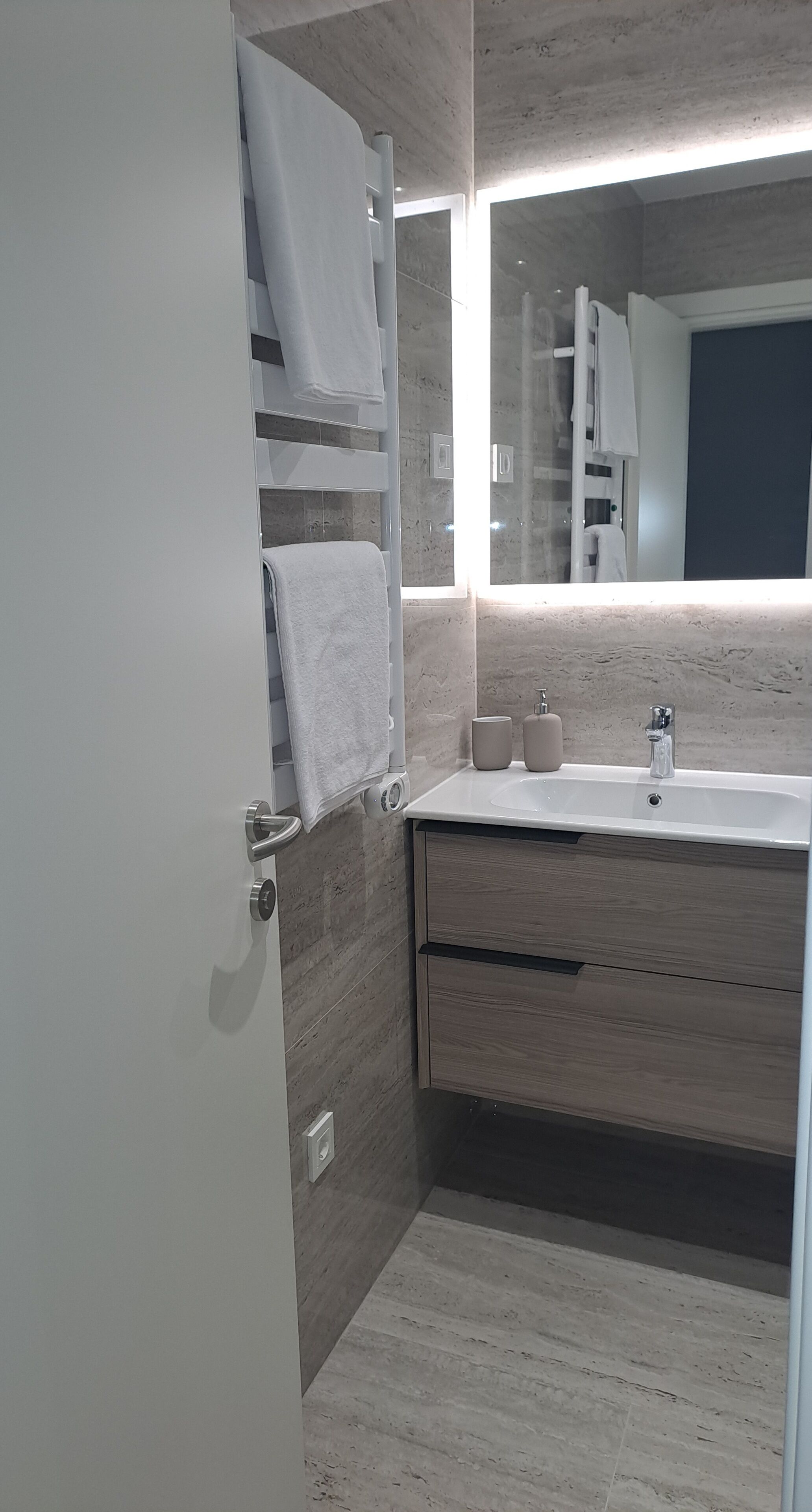 Un baño moderno con un tocador de madera, un espejo grande y un perchero para toallas.