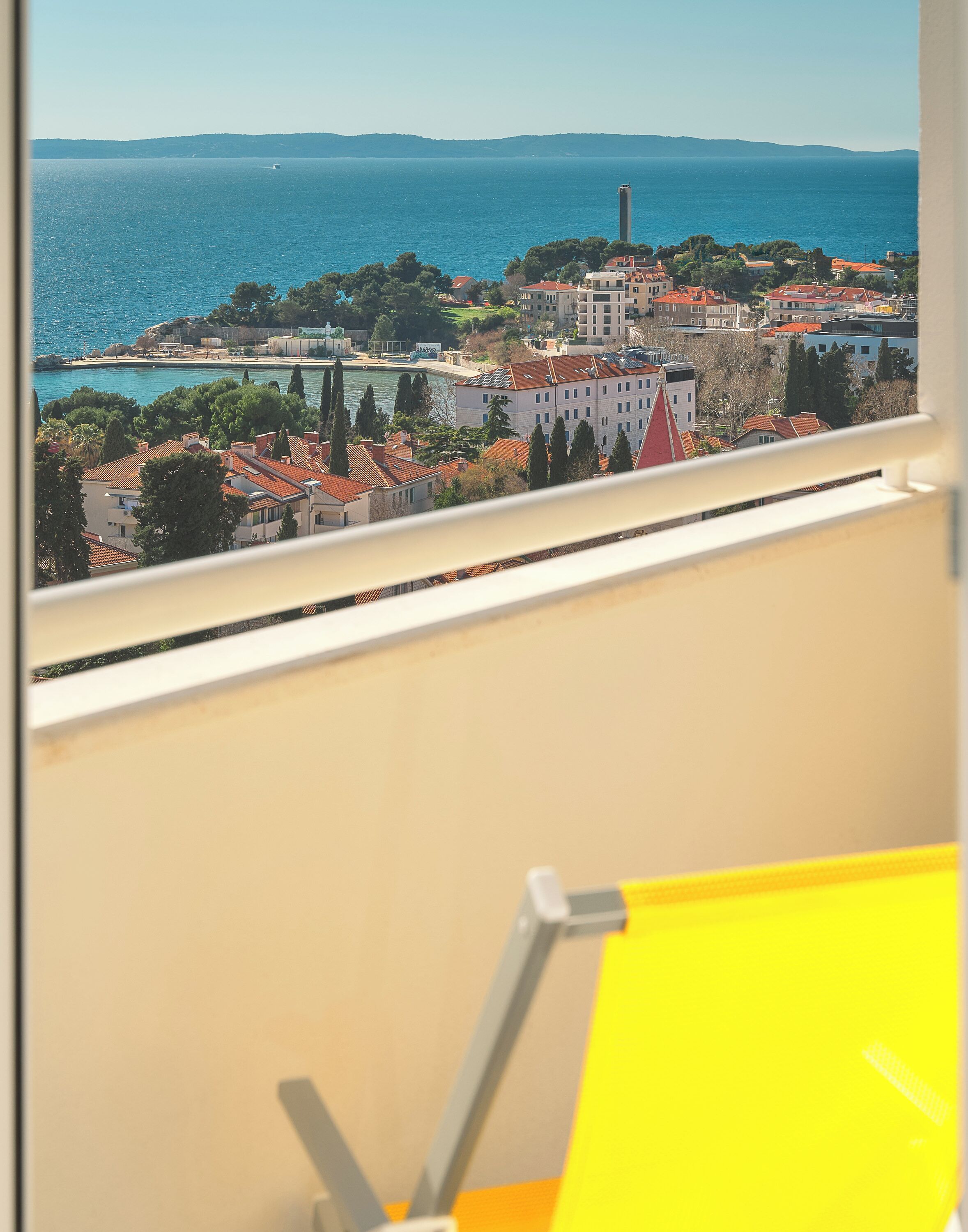 A coastal cityscape with buildings, a lighthouse, and a view of the sea.