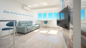 A modern living room with a sofa, a dining area, and a TV mounted on the wall. - Apartments 4 You in Split (Split)