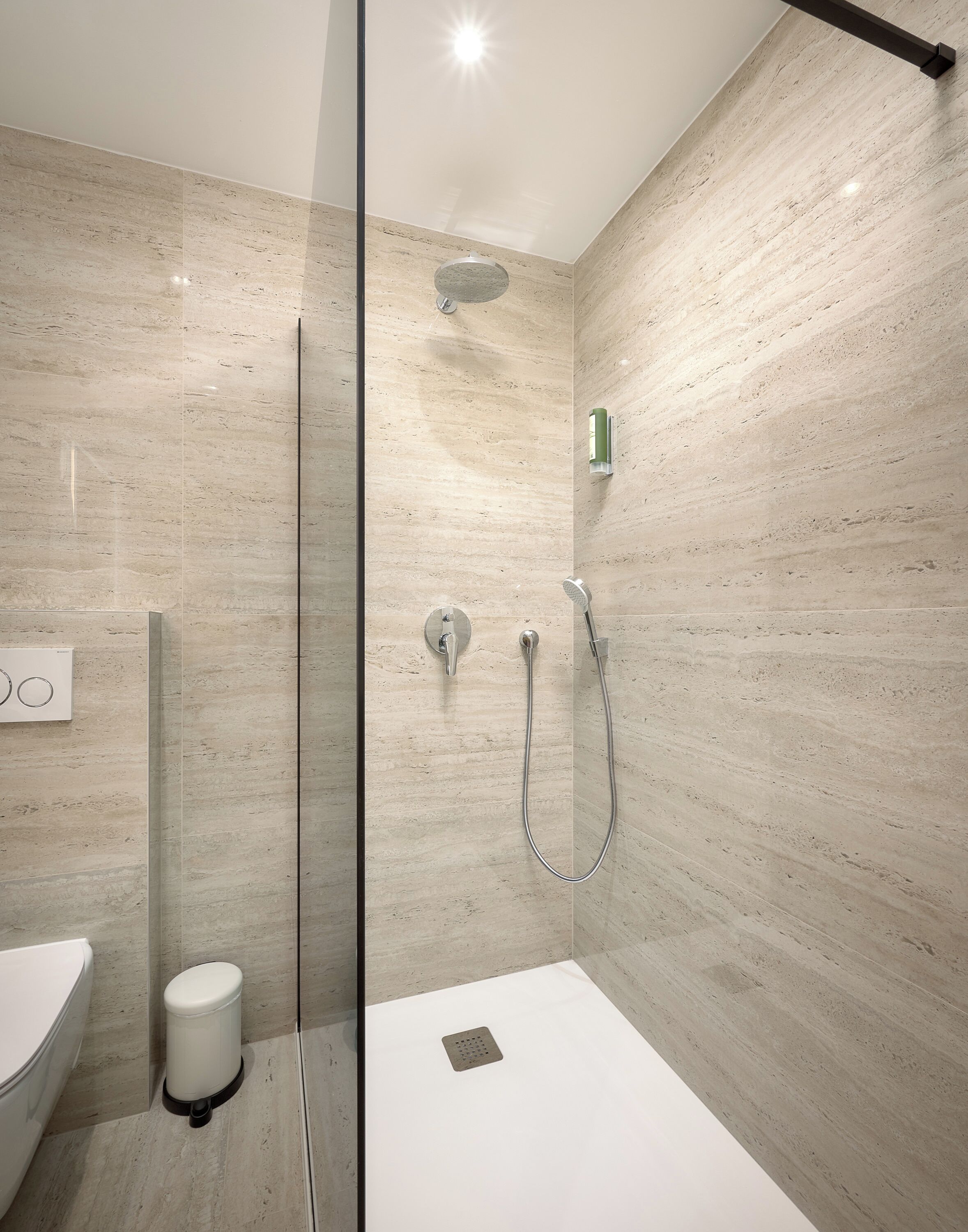Ein modernes Badezimmer mit einer Duschkabine, einem weißen Waschbecken und einer Toilette.