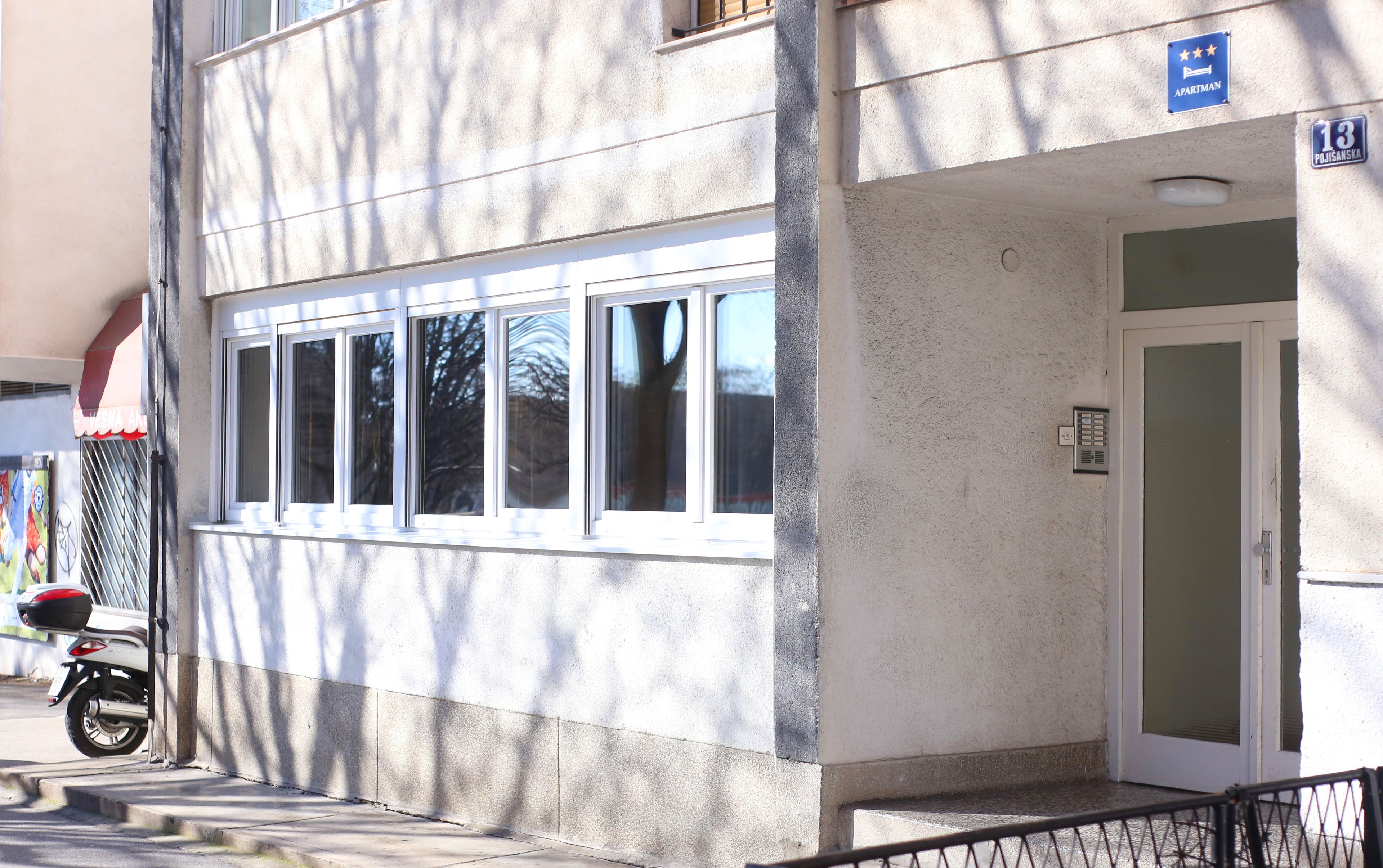 A building with a white facade, a door with a glass panel, and a sign indicating it is an apartment.