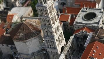 Un bâtiment historique doté d’un imposant clocher et d’un dôme circulaire, entouré d’une architecture traditionnelle avec des toits recouverts de tuiles rouges.