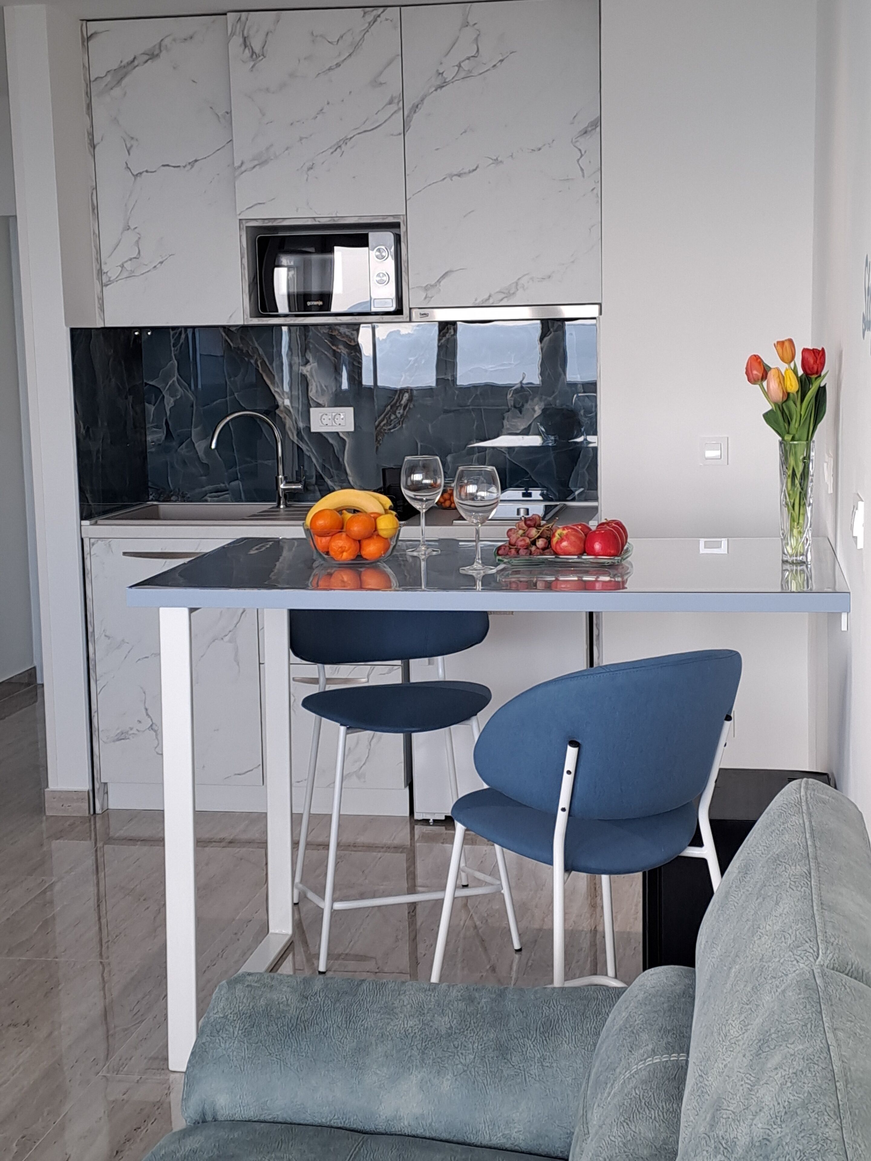 Una cocina moderna con salpicadero de mármol, una isla central con asientos y un jarrón de tulipanes en la encimera.