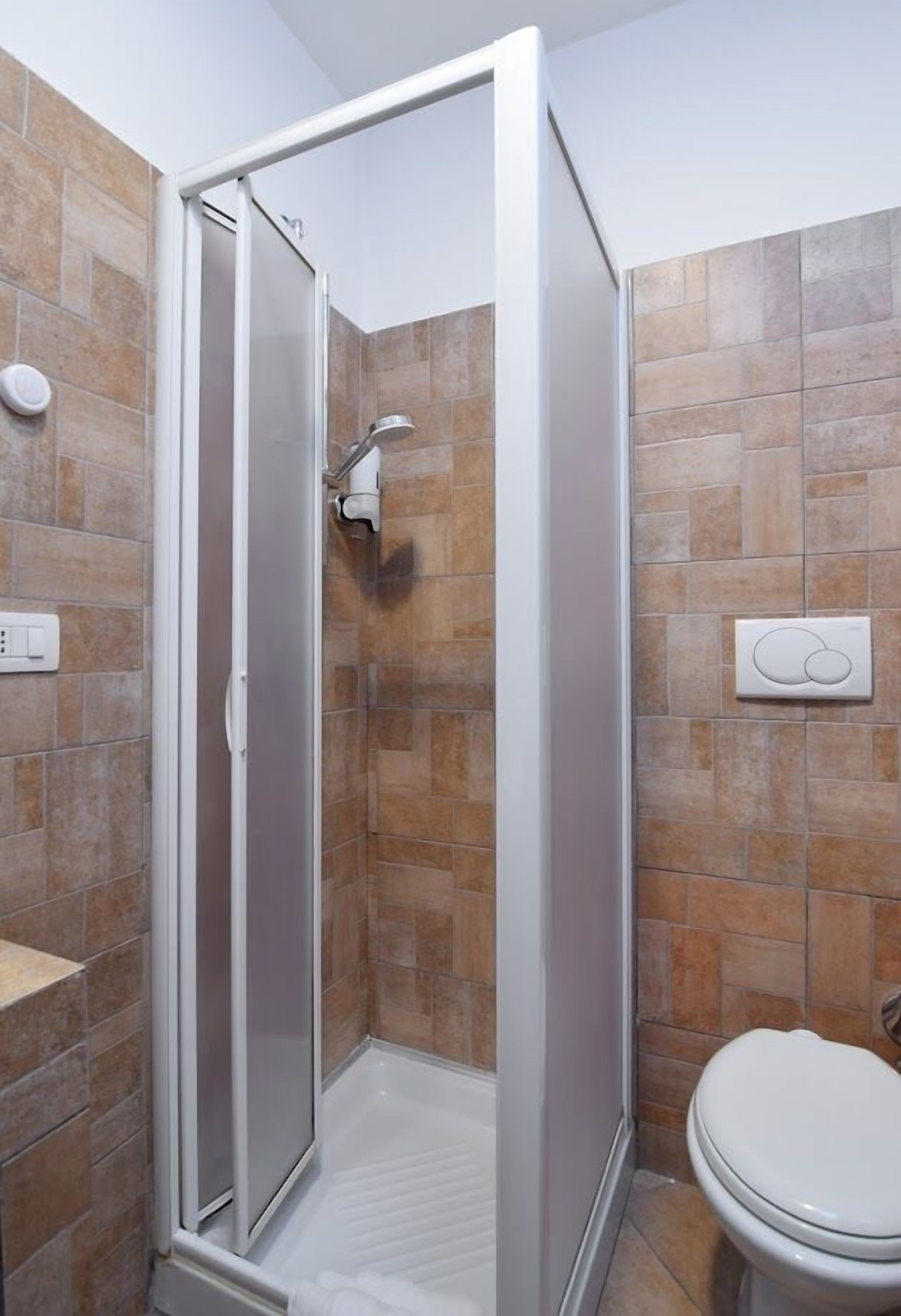 A bathroom with a shower enclosure, a toilet, and a wall-mounted hand dryer.