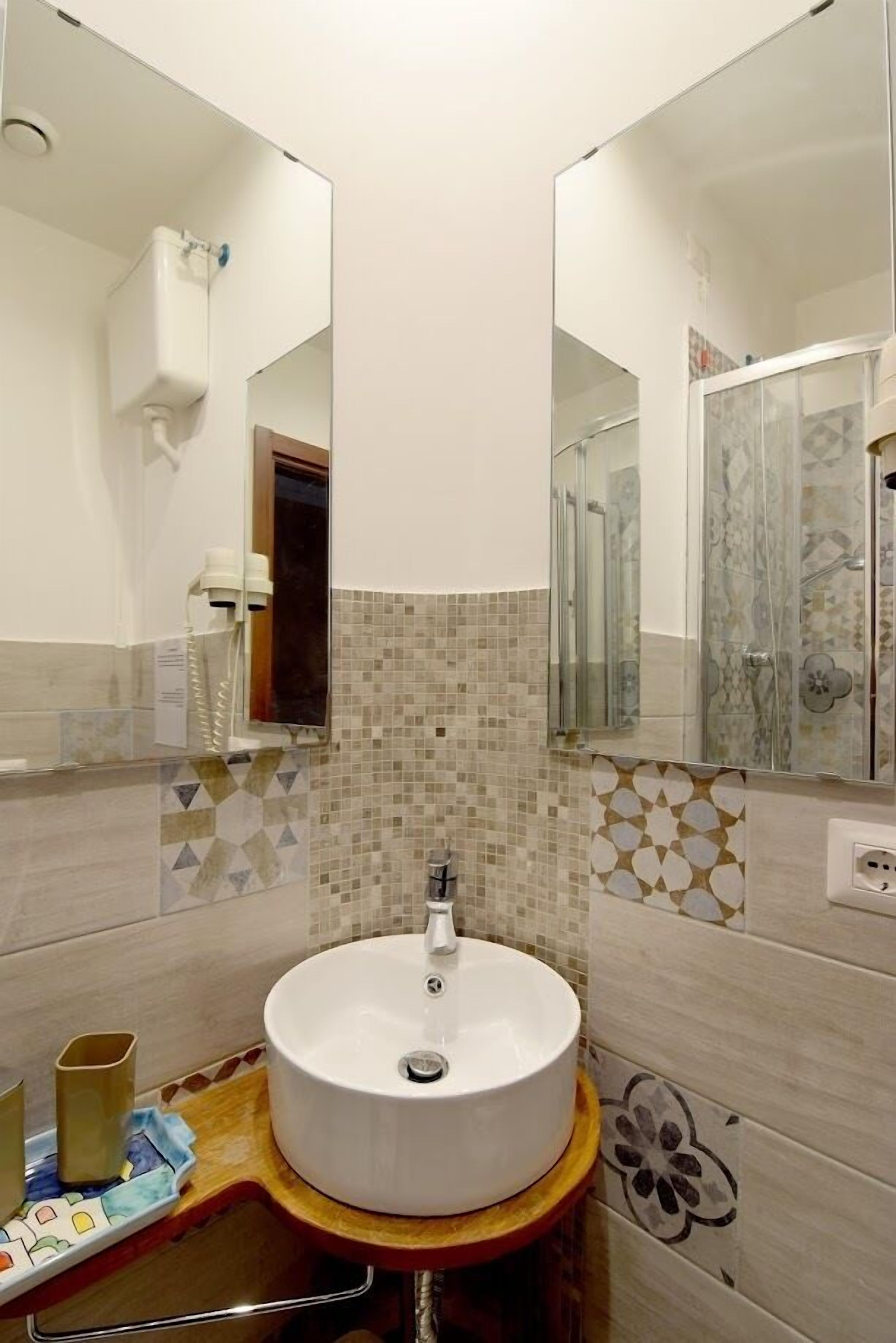 A bathroom with a round sink, a mirror, and a shower.