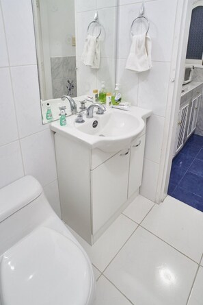 A bathroom with a white sink, toilet, and a mirror. There are two towels hanging on the wall. - B&B El Olivar (Lima)