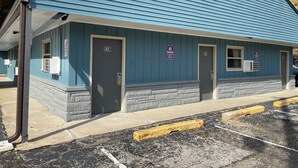 A building with two doors labeled 41 and 42, a blue exterior, and a parking area with yellow curbs. - Royal Motel (Martinsville)
