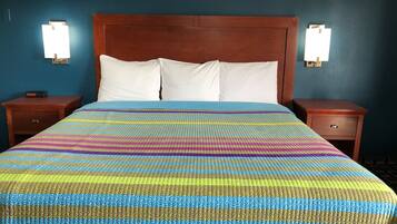 A bed with a colorful striped bedspread, wooden headboard, two bedside tables, and wall-mounted lamps.