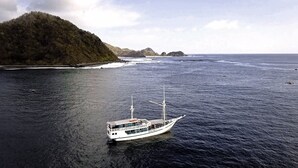 Una barca su acque calme con una costa montuosa sullo sfondo.