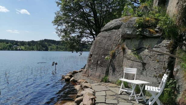 Un banco junto al lago, con un fondo rocoso y una vista despejada del agua.