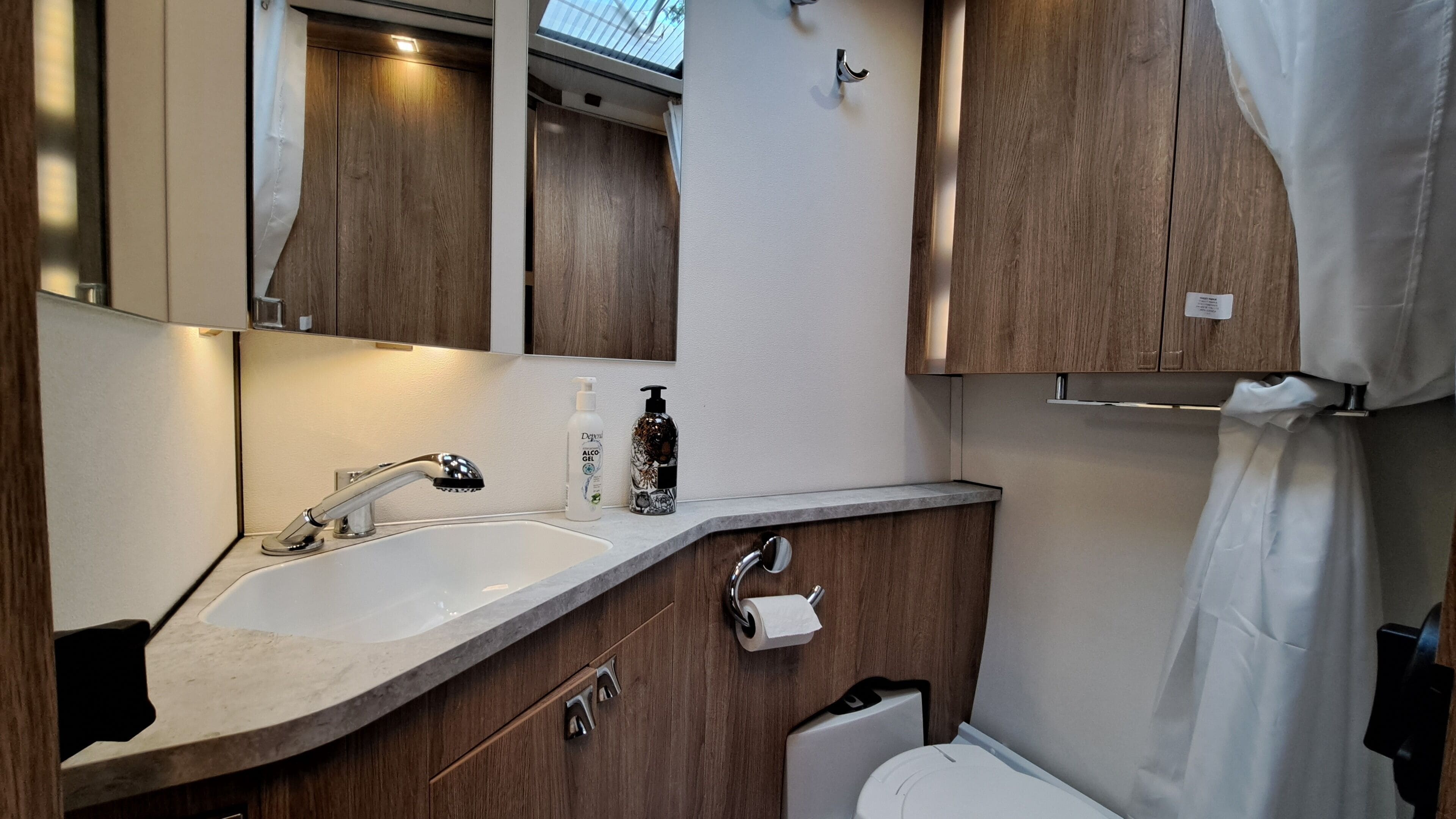 A modern bathroom with a sink, mirror, and wooden cabinets.