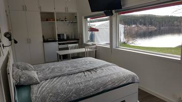 Un dormitorio con cama, escritorio y ventana con vistas a un lago.