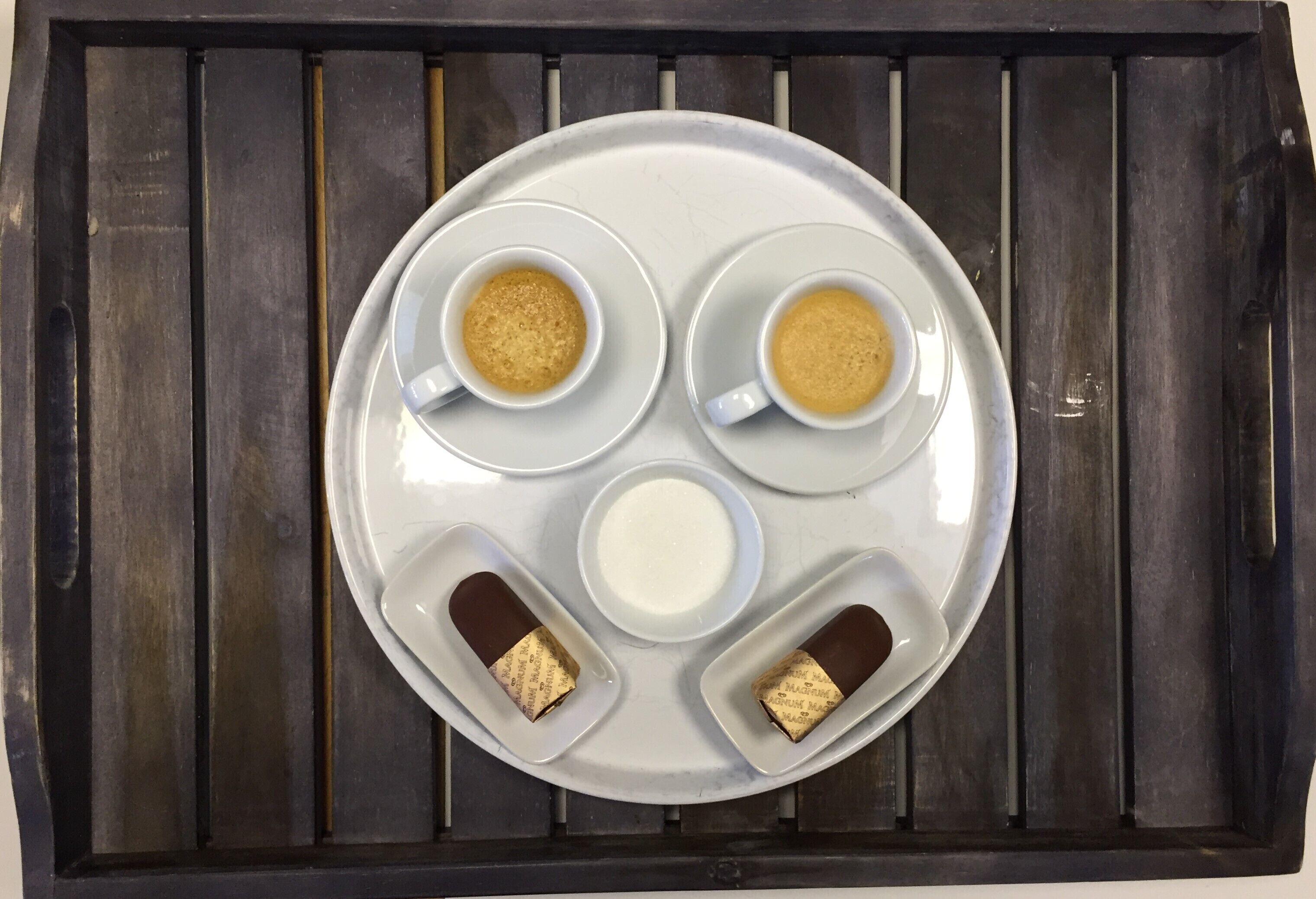 A tray with two cups of coffee, a glass of milk, and two chocolate bars.